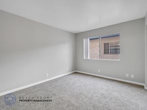 Long Beach apartment for rent - A spacious room with a carpeted floor and a window showing a building outside.