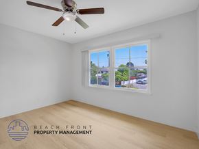 Los Angeles apartment for rent - A room with a ceiling fan and a window showing a view of a street and buildings.