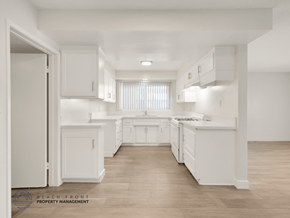 Inglewood apartment for rent - A white kitchen with wooden floors and a logo for Beach Front Property Management in the bottom left corner.