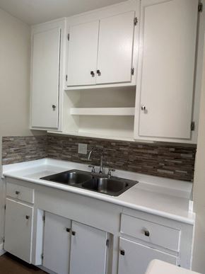 Anaheim apartment for rent - A kitchen with white cabinets and a stone backsplash.