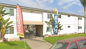 Norwalk apartment for rent - A red car is parked in front of a white building with a red and yellow sign that reads