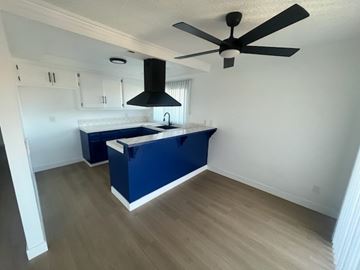 Westminster apartment for rent - A kitchen with a blue island and a fan.