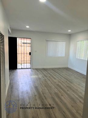 Tustin apartment for rent - an empty living room with wood floors and a door to a balcony