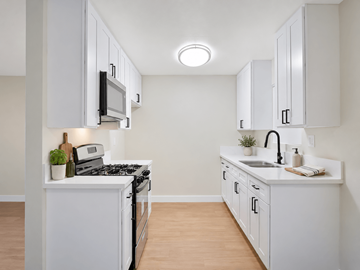 Downey apartment for rent - A white kitchen with a black stove top oven and a black microwave.