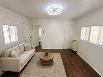 Signal Hill apartment for rent - A living room with a white couch, a wooden coffee table, and a ceiling fan.