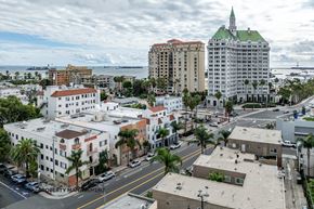 Long Beach apartment for rent - A cityscape with a mix of modern and older buildings, palm trees, and a cloudy sky.