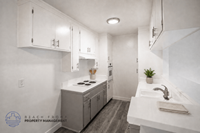Long Beach apartment for rent - A clean, white kitchen with a sink, stove, and cabinets.