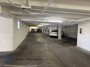Long Beach apartment for rent - A parking garage with a few cars and a logo that says "Beach Front Property Management".