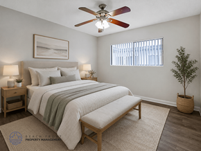 Downey apartment for rent - A bedroom with a bed, a bench, a ceiling fan, and a potted plant.