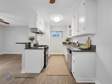 Downey apartment for rent - A kitchen with white cabinets and a black countertop.