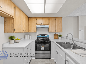 Santa Ana townhouse for rent - A kitchen with wooden cabinets and a stove top oven.