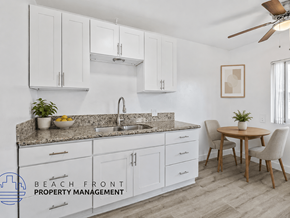 Long Beach apartment for rent - A kitchen with white cabinets and a countertop with a sink and a potted plant.