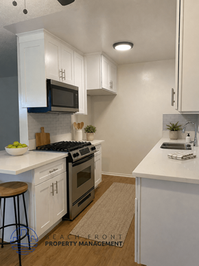 Buena Park apartment for rent - A modern kitchen with white cabinets and a black stove top oven.