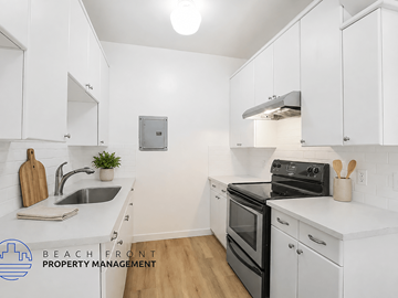 Long Beach apartment for rent - A kitchen with white cabinets and a black stove top oven.