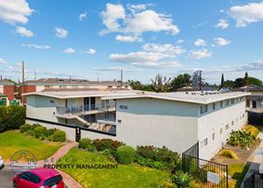 Downey apartment for rent - a large white building with a red car parked in front of it