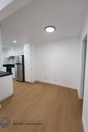 Long Beach apartment for rent - A kitchen with white cabinets and a black countertop with a stainless steel refrigerator.