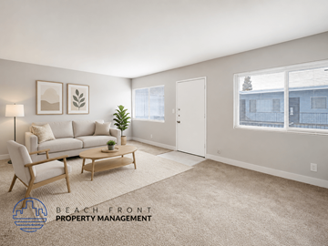 Long Beach apartment for rent - A living room with a white couch, a wooden chair, and a small table with a plant on it.
