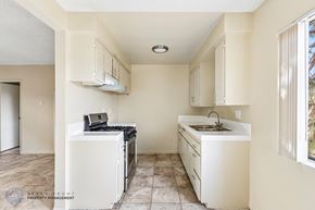 Hawthorne apartment for rent - A kitchen with a white fridge, sink, and cabinets.