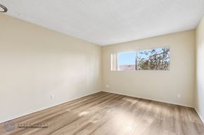 Hawthorne apartment for rent - A room with wooden flooring and a window showing a tree and a building outside.