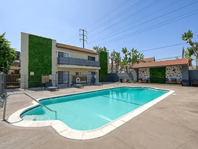 Downey apartment for rent - A small residential building with a green wall and a pool in front.