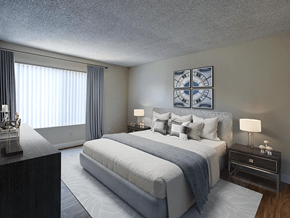 Downey apartment for rent - A bedroom with a large bed and a nightstand with a lamp.