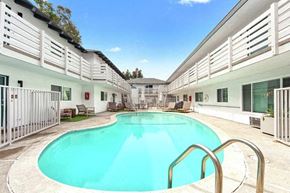 Newport Beach apartment for rent - A swimming pool in a sunny day surrounded by white buildings.