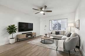 Hawthorne apartment for rent - A living room with a grey couch, a television, a plant, and a fan.