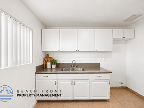 Cudahy apartment for rent - A kitchen with white cabinets and a countertop with a sink and a potted plant.