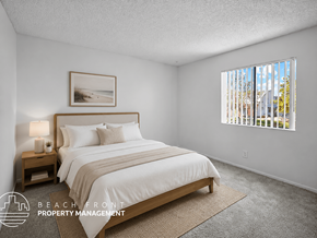 Los Angeles apartment for rent - A bedroom with a large bed and a window showing a view of a beach.