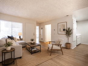 Pomona apartment for rent - A living room with a grey couch, a wooden chair, a coffee table, and a small tree.