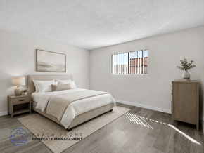 Long Beach apartment for rent - A well-lit bedroom with a large bed and a wooden nightstand.