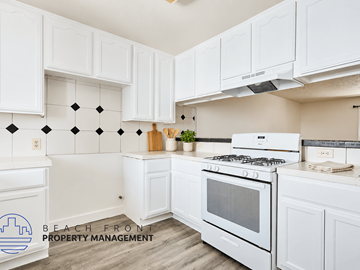 Long Beach apartment for rent - A kitchen with white cabinets and a white stove top oven.