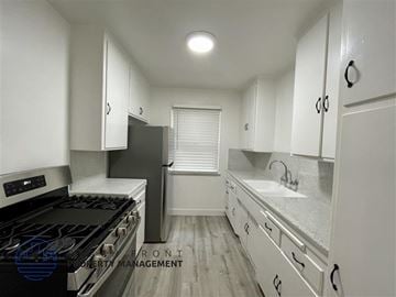 Redondo Beach apartment for rent - A kitchen with white cabinets and a black stove top oven.