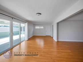San Pedro apartment for rent - A spacious room with wooden flooring and a logo for Beach Front Property Management in the corner.