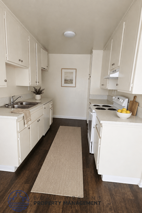 Inglewood apartment for rent - A kitchen with white cabinets and a beige rug on the floor.