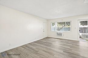 Downey apartment for rent - A spacious room with wooden flooring and a window with blinds.