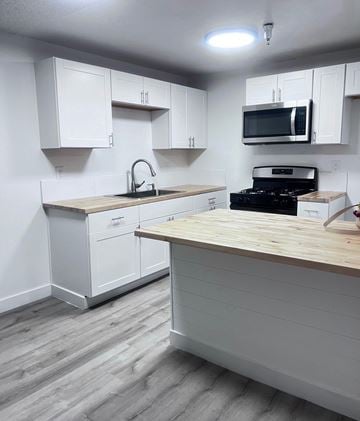 Santa Ana apartment for rent - A kitchen with white cabinets and a wooden counter.