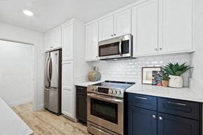 Newport Beach apartment for rent - A kitchen with white cabinets and a black stove top oven.