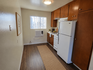 Gardena apartment for rent - A kitchen with a white refrigerator and wooden cabinets.