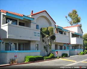 Paramount apartment for rent - A building with a red tile roof and a white facade with blue trim.
