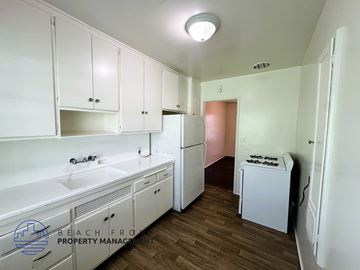 Long Beach apartment for rent - A kitchen with white cabinets and a white fridge.