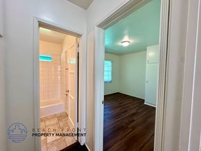 Long Beach apartment for rent - A hallway with a doorway leading to a bathroom with a tiled shower.