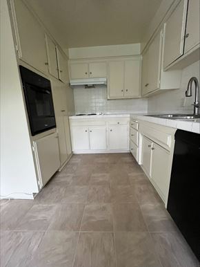 Torrance apartment for rent - an empty kitchen with white cabinets and black appliances
