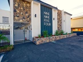 Bellflower apartment for rent - A building with a stone wall and a sign that reads "NINE FIVE FOUR".