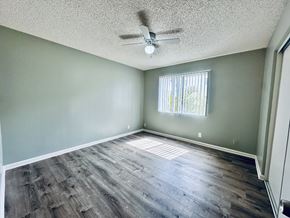 Long Beach apartment for rent - A room with a ceiling fan and a window with blinds.