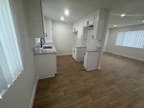 Downey apartment for rent - A kitchen with white cabinets and a wooden floor.