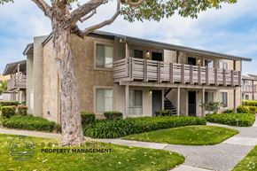 Westminster apartment for rent - A tree stands in front of a building with the words "Beachfront Property Management" written on it.