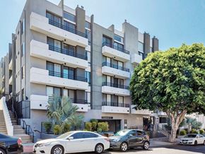 Los Angeles apartment for rent - a large white apartment building with cars parked in front of it