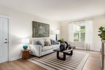 Grove City townhouse for rent - A living room with a grey couch, a wooden side table with a blue vase, a coffee table, and a painting on the wall.