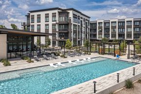 Houston apartment for rent - a swimming pool with chaise lounge chairs and a building in the background